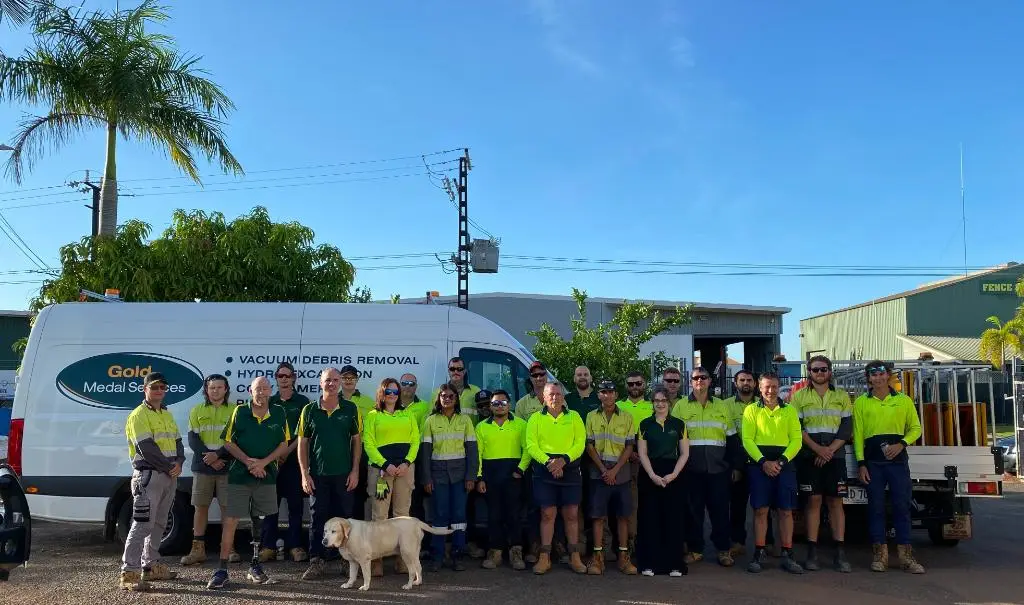 Work crew posing in front of company vehicles