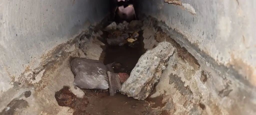 Rocks and debris inside a narrow concrete drain