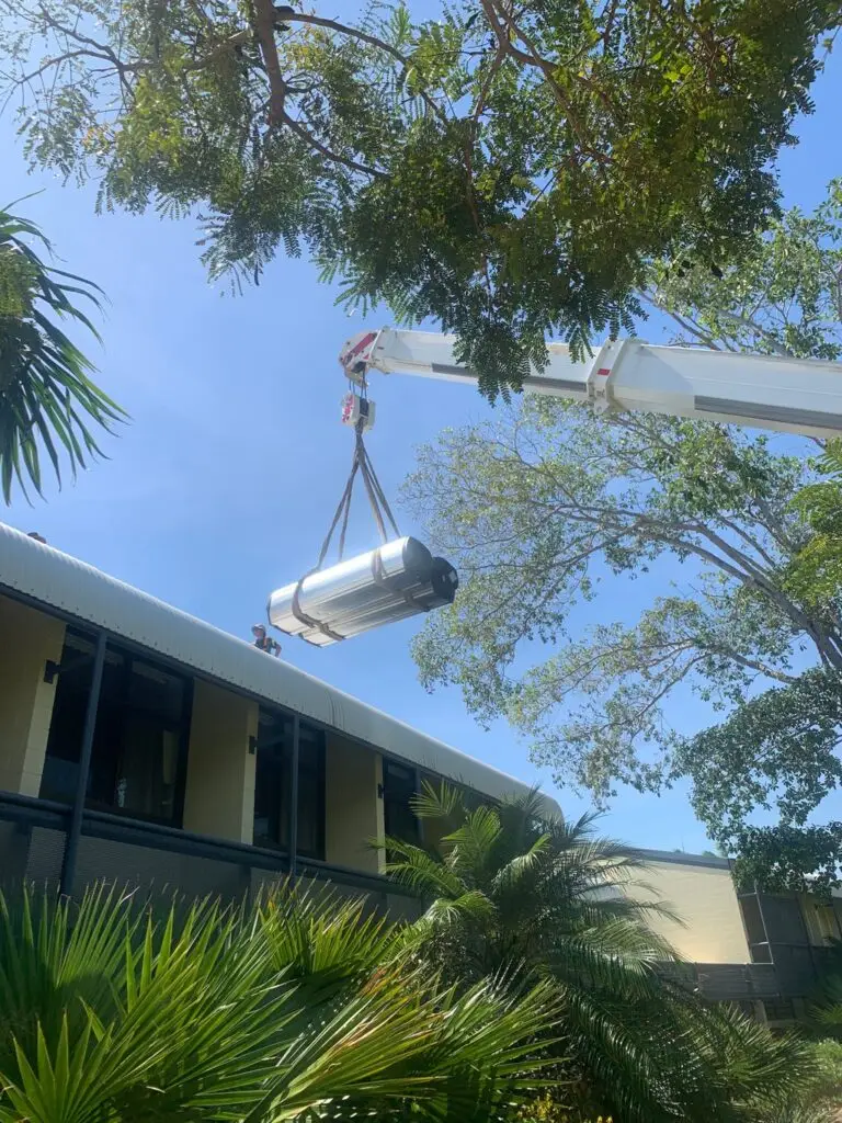 Crane lifting water tank onto building roof